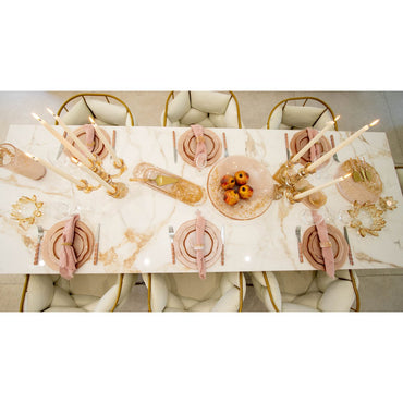 Elegant table setting with marble tablecloth, gold cutlery, and pink napkins.