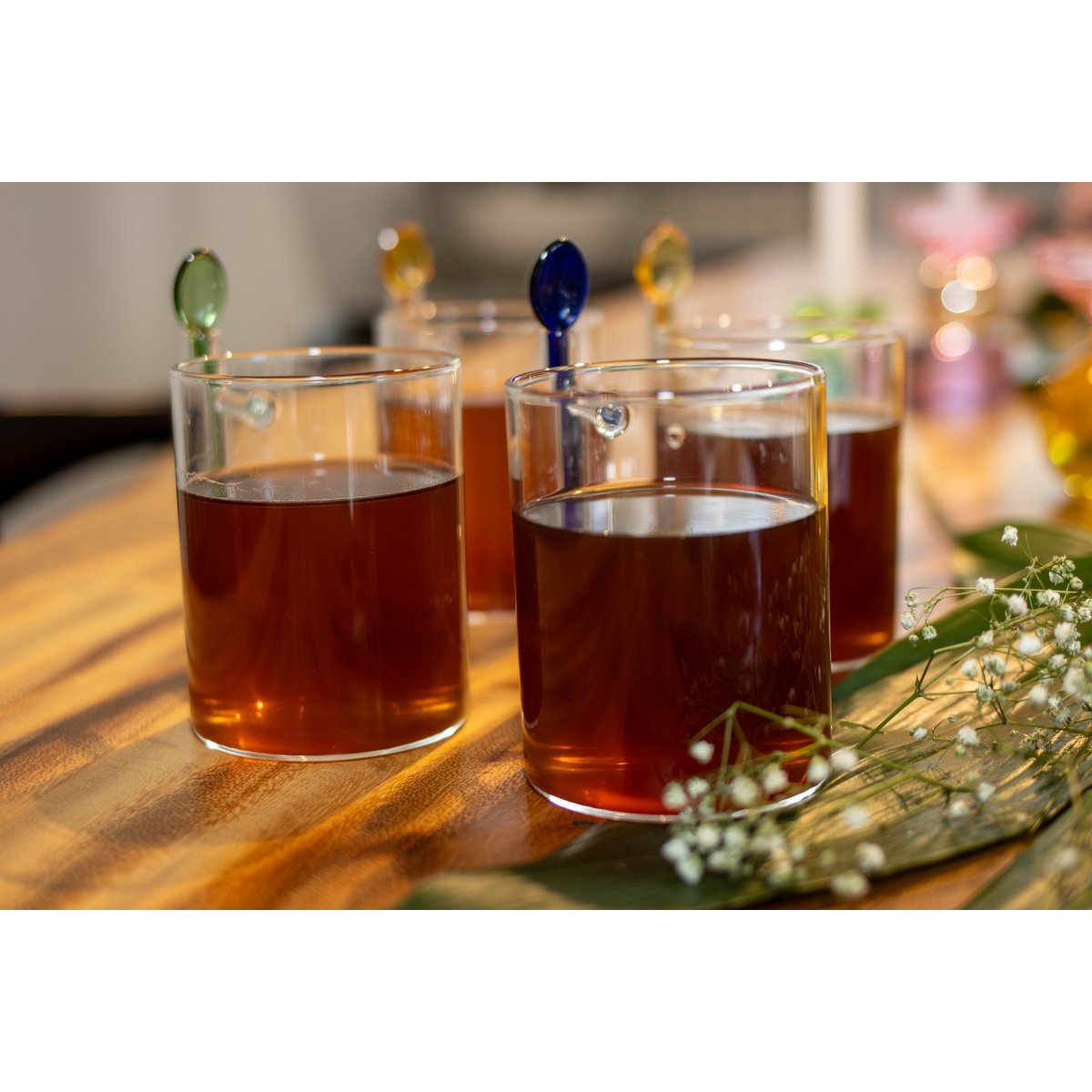 Four glasses of amber-colored liquid on a wooden surface with blurred background