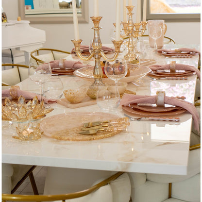 Elegant dining table setting with gold and pink accents on a marble surface.