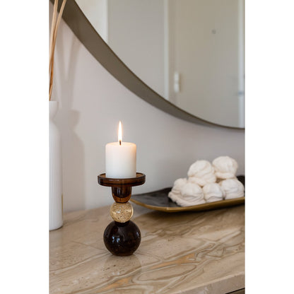 Candle in a decorative holder on a marble surface with a mirror in the background